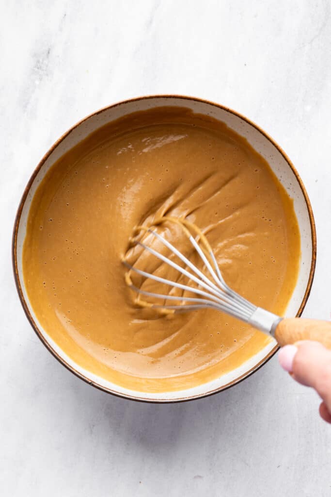 This 4-ingredient peanut sauce recipe yields a smooth, savory, tangy sauce with the perfect spice kick. Ditch the takeout. Make it at home! Whisking together soy sauce, peanut butter, sriracha, and lime juice.