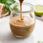 Drizzling peanut sauce into a jar.