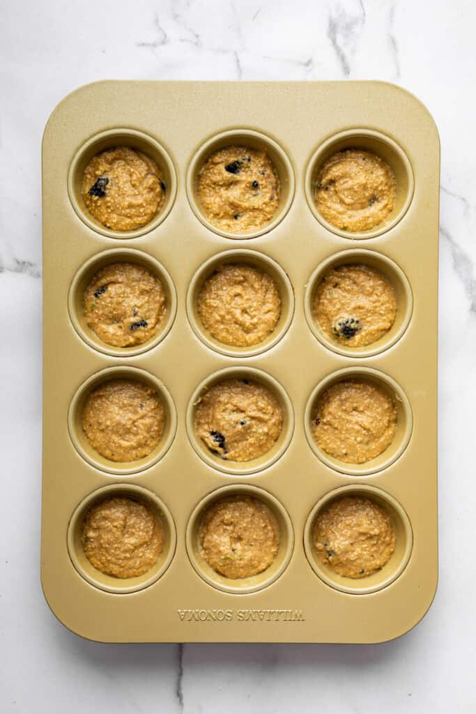 Topped with a smooth coconut-lime glaze, these easy, tender, GF blackberry muffins are a fabulous way to celebrate berry season. Blackberry muffin batter in muffin tines, ready to be baked.