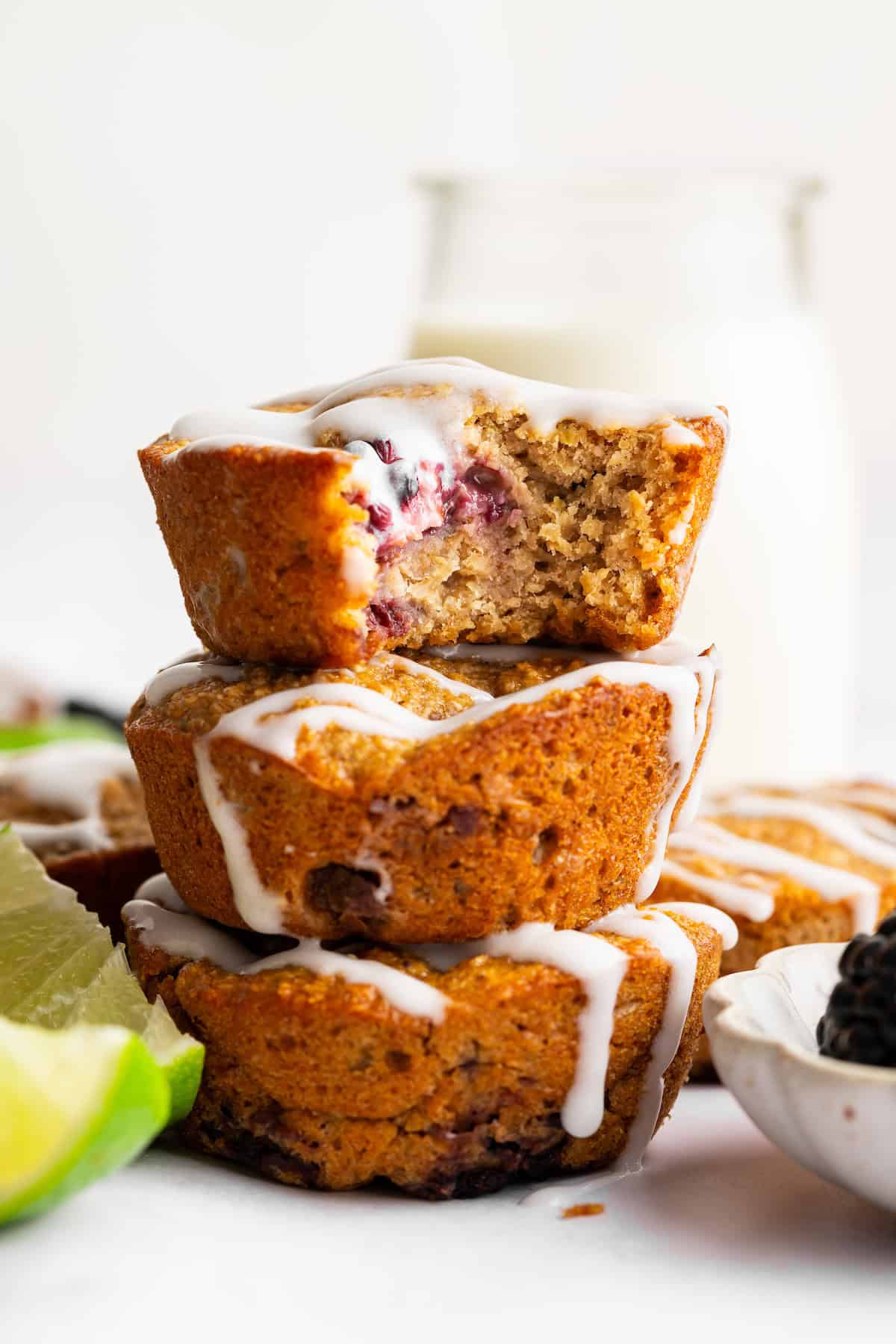 Topped with a smooth coconut-lime glaze, these easy, tender, GF blackberry muffins are a fabulous way to celebrate berry season. A stack of blackberry lime muffins.
