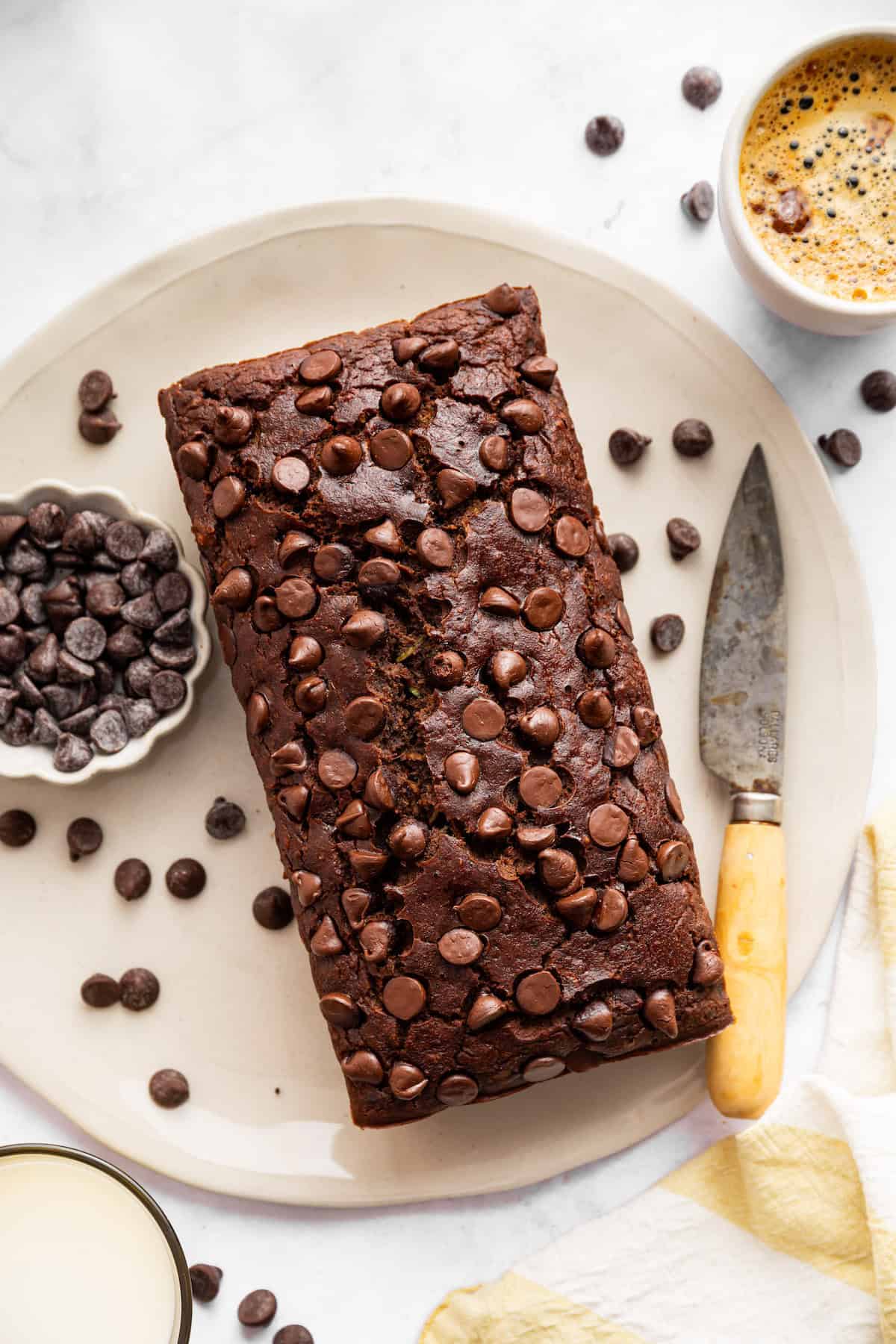 This vegan chocolate chip zucchini bread is incredibly tender, and the rich, earthy chocolate-zucchini combo is to die for. A loaf of gluten-free chocolate zucchini bread on a plate.
