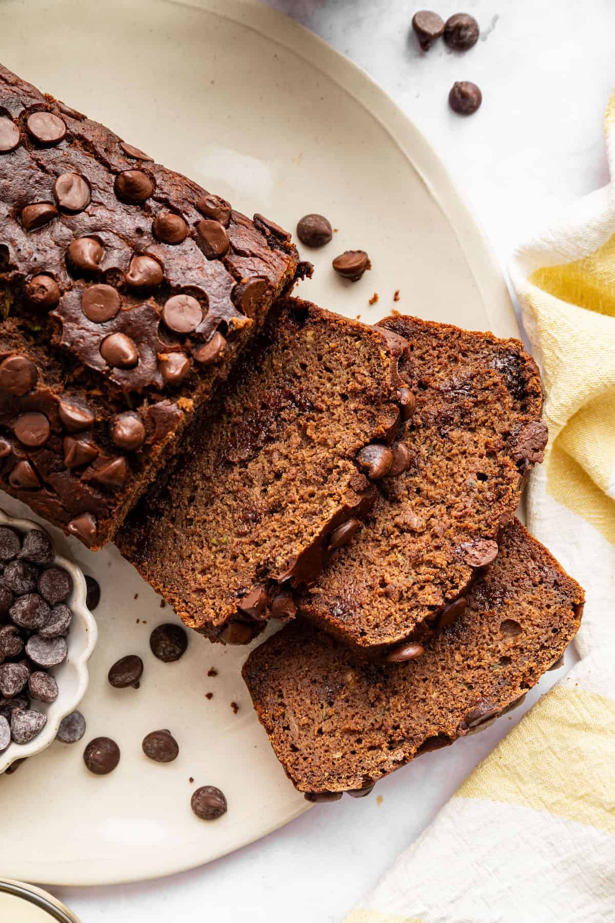 This vegan chocolate chip zucchini bread is incredibly tender, and the rich, earthy chocolate-zucchini combo is to die for. Sliced chocolate zucchini bread on a plate.