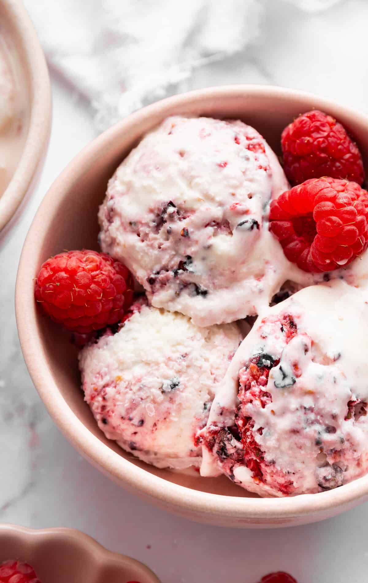 This Greek yogurt ice cream is smooth, creamy, packed with protein, and lightly sweetened with honey and a colorful swirl of fresh berries. Close-up image of a bowl of Greek yogurt ice cream with berries.