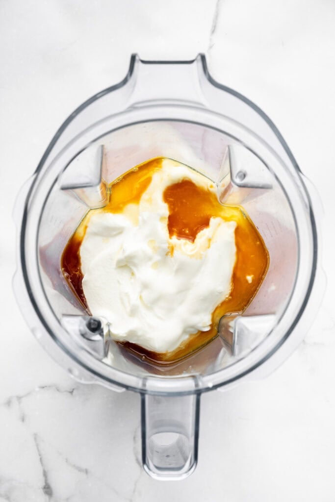 This Greek yogurt ice cream is smooth, creamy, packed with protein, and lightly sweetened with honey and a colorful swirl of fresh berries. Adding Greek yogurt, honey, and vanilla to a blender.