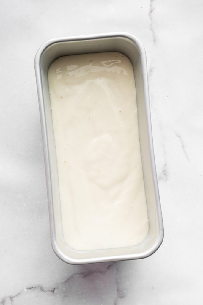 This Greek yogurt ice cream is smooth, creamy, packed with protein, and lightly sweetened with honey and a colorful swirl of fresh berries. Adding half of the Greek yogurt ice cream base to a loaf pan.
