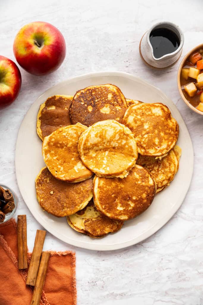 These fluffy apple cider pancakes aren't holding back on apple flavor. The apple cider really does the trick. And that hint of cinnamon? Yes! A plate loaded with apple cider pancakes ready to be dolled up with maple syrup.
