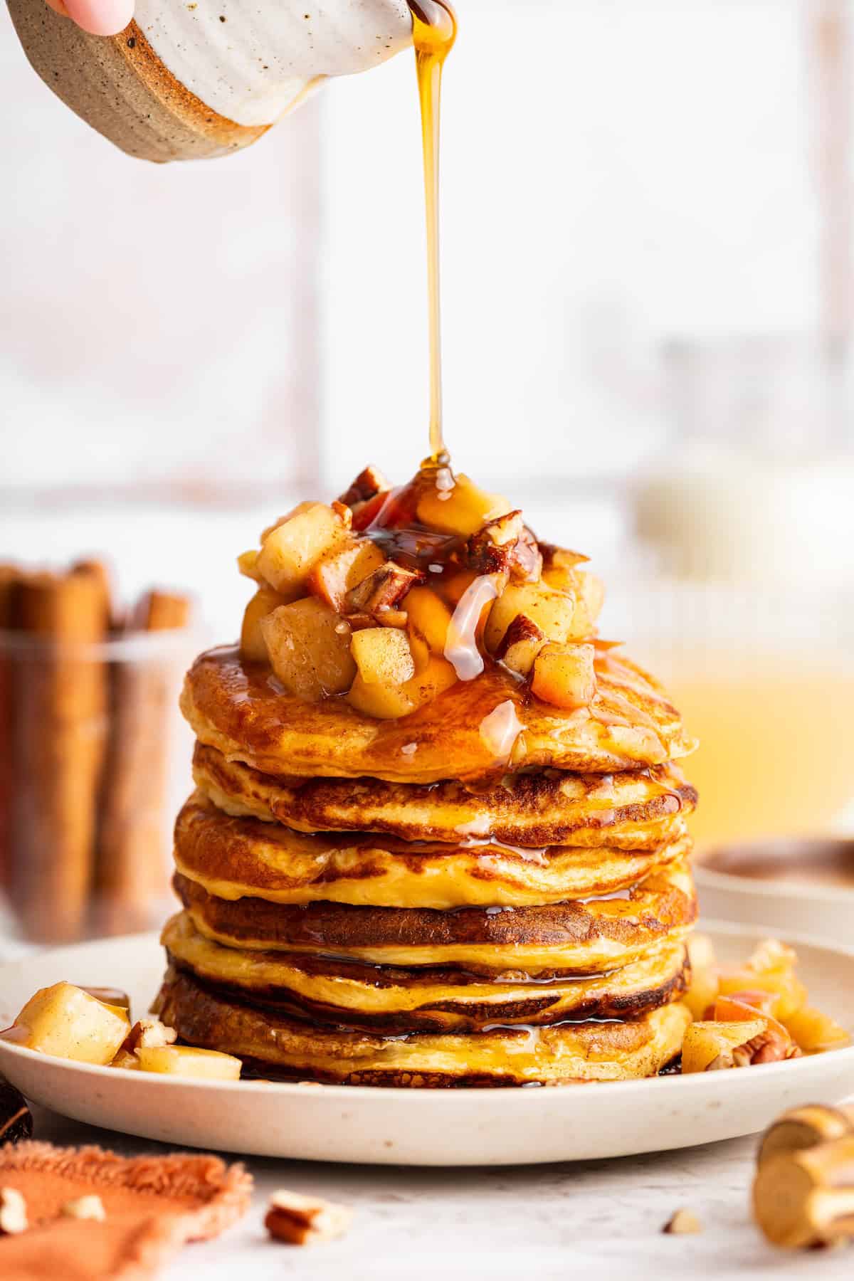 These fluffy apple cider pancakes aren't holding back on apple flavor. The apple cider really does the trick. And that hint of cinnamon? Yes! Pouring maple syrup over a stack of apple cider pancakes.