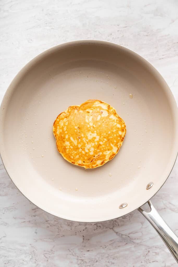 These fluffy apple cider pancakes aren't holding back on apple flavor. The apple cider really does the trick. And that hint of cinnamon? Yes! A perfectly cooked apple pancake in a pan.