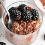 A spoon diving into creamy chocolate chia pudding in a jar.