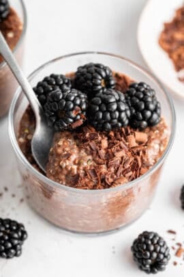 A spoon diving into creamy chocolate chia pudding in a jar.
