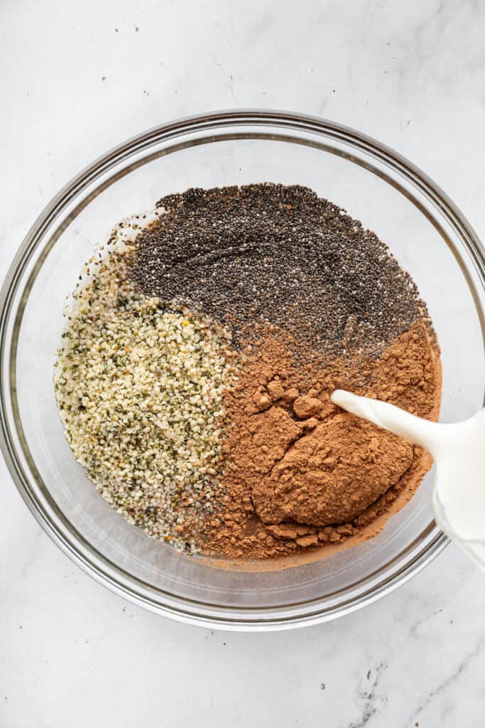 This creamy 5-ingredient chocolate chia pudding packs a powerful punch of protein and just-sweet-enough chocolate pizzaz. And it's so easy! Combining chia seeds, hemp seeds, cocoa powder, almond milk, and water in a bowl.