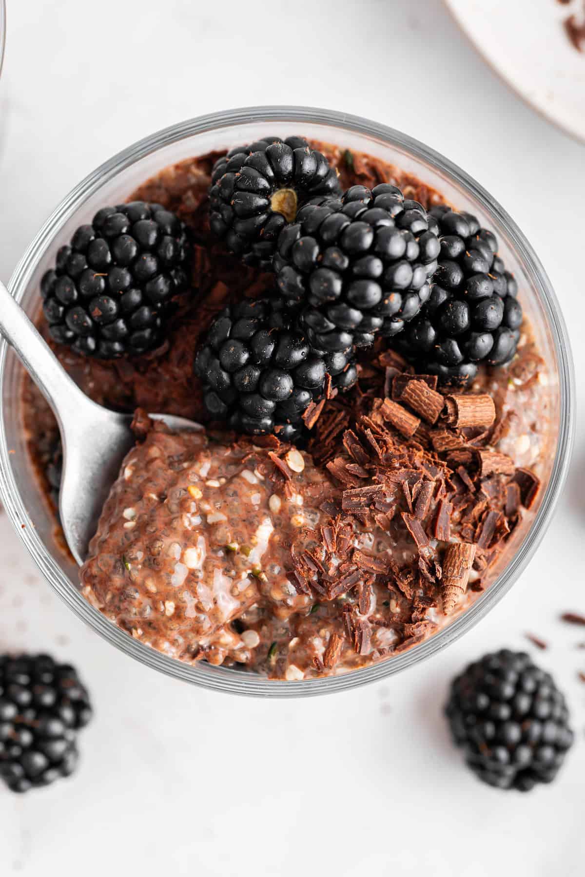 This creamy 5-ingredient chocolate chia pudding packs a powerful punch of protein and just-sweet-enough chocolate pizzaz. And it's so easy! Overhead image of a spoon diving into creamy chocolate chia pudding in a jar.