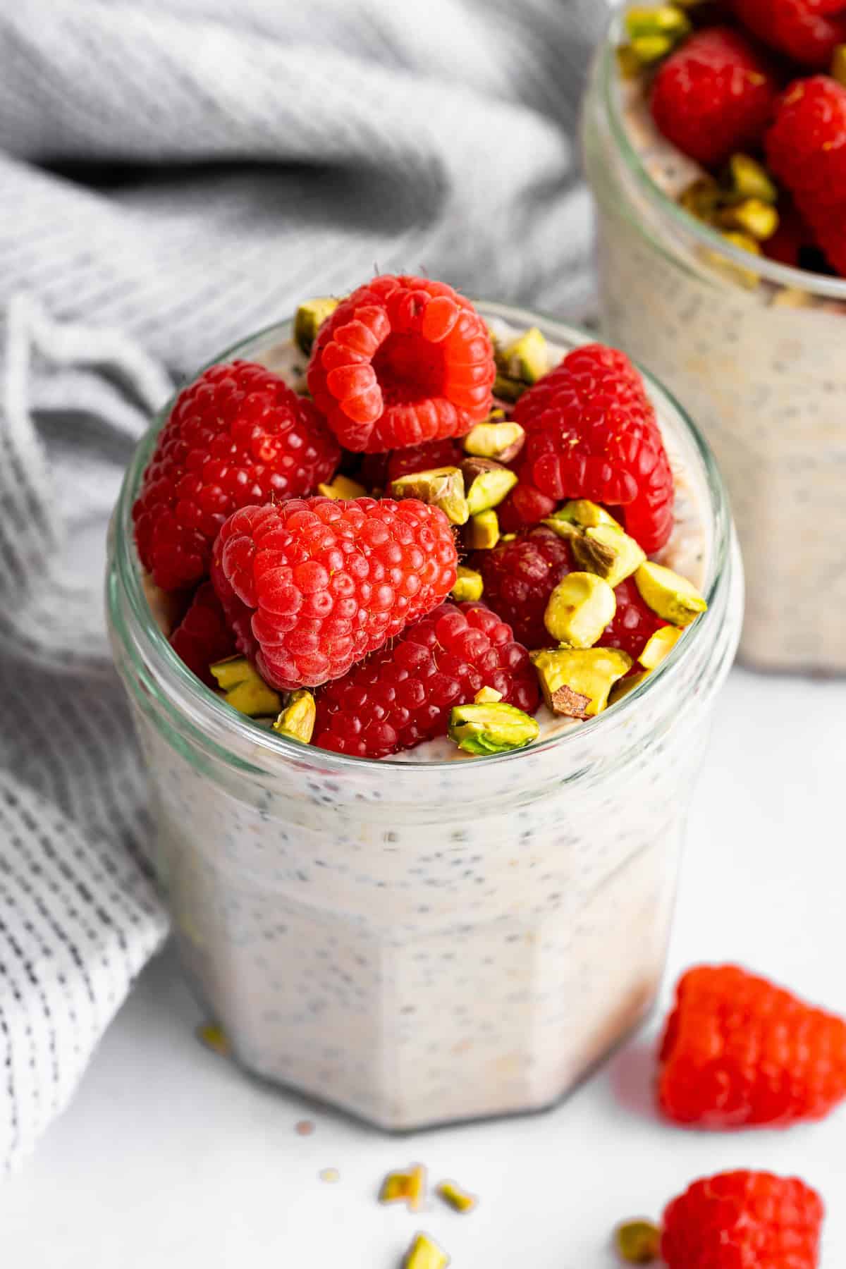These high-protein overnight oats are so thick and creamy with a little tang from Greek yogurt and a hit of sweetness from maple syrup. A jar of high protein overnight oats topped with berries and pistachios.
