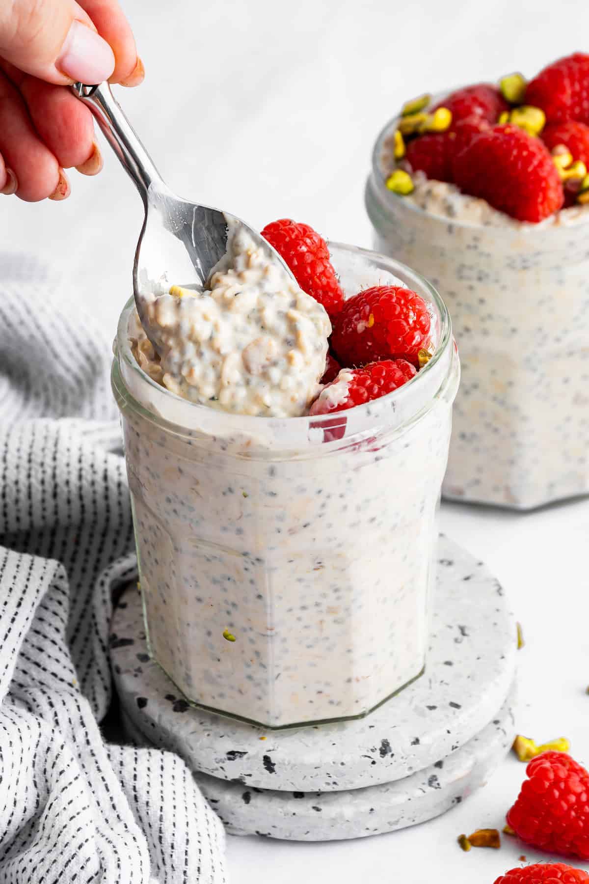 These high-protein overnight oats are so thick and creamy with a little tang from Greek yogurt and a hit of sweetness from maple syrup. A spoon scooping into a jar of high protein overnight oats.