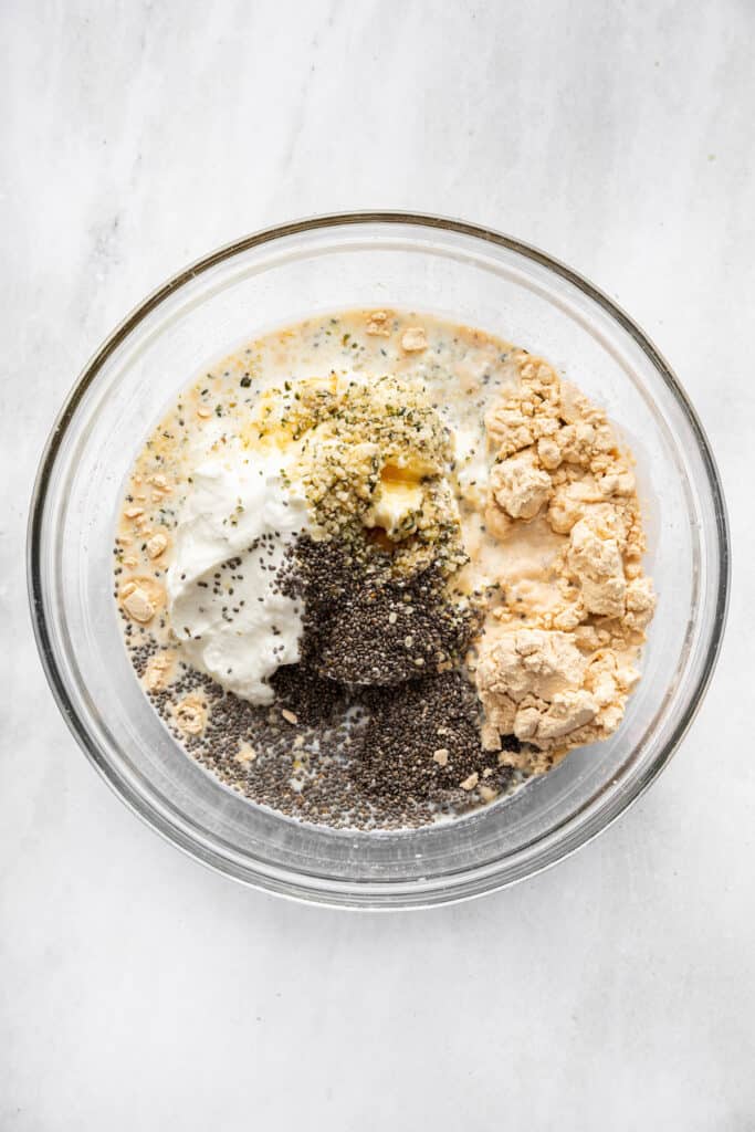 These high-protein overnight oats are so thick and creamy with a little tang from Greek yogurt and a hit of sweetness from maple syrup. A jar full of oats, seeds, Greek yogurt, milk, maple syrup, and protein powder.