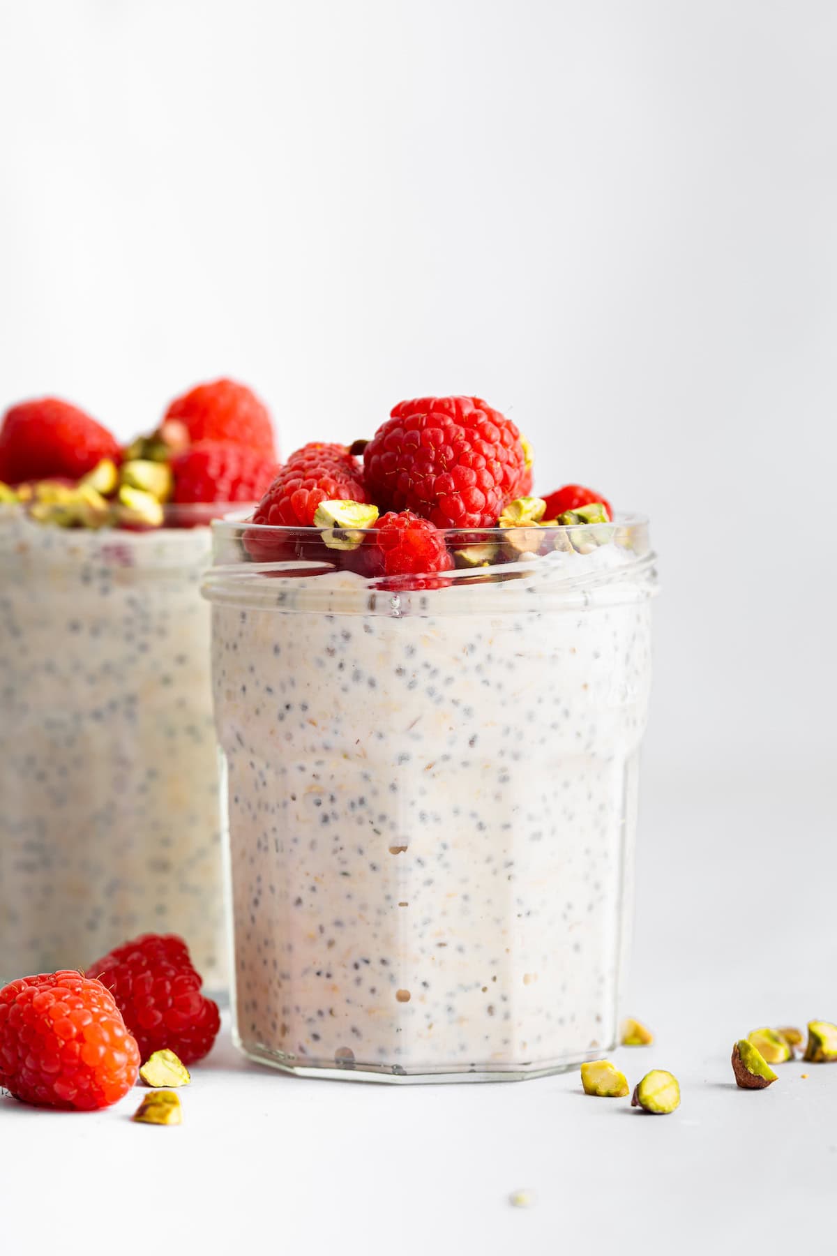 These high-protein overnight oats are so thick and creamy with a little tang from Greek yogurt and a hit of sweetness from maple syrup. Two jars of high protein overnight oats topped with berries and pistachios.