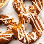 Pumpkin donuts scattered on a surface. One has a bite taken out of it.