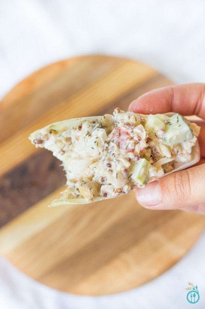 A bite taken from an endive "boat" filled with creamy salad.